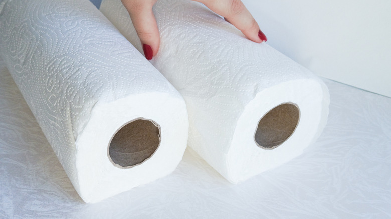 Bàn tay sơn móng tay màu đỏ chạm vào một trong hai cuộn khăn giấy