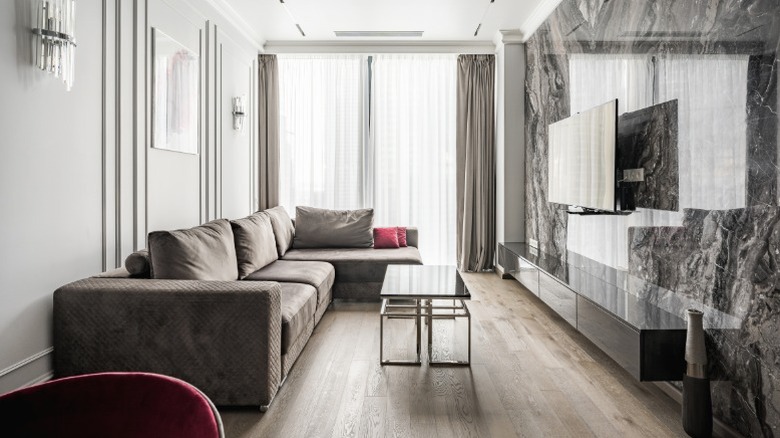 Phòng khách hẹp hiện đại với các chi tiết theo chiều dọc để thu hút ánh nhìn, bao gồm rèm kéo dài từ trần đến sàn, đèn treo tường và khuôn đúc