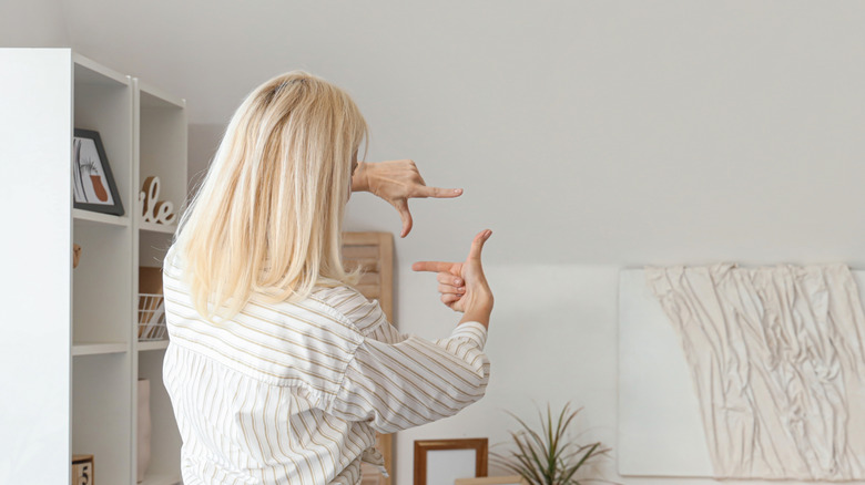 Người phụ nữ nhìn vào bức tường trống và dự định sẽ làm gì với nó