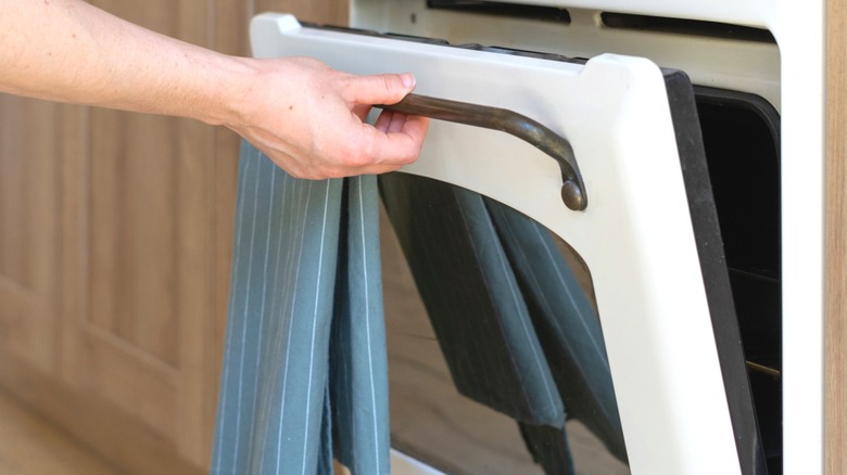 Người mở cửa lò với khăn lau bếp trên tay nắm cửa