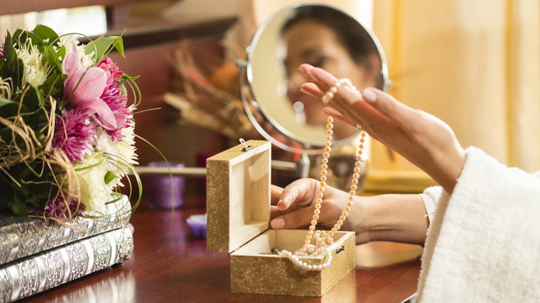Một người phụ nữ lấy ra những chiếc vòng cổ dài từ hộp trang sức