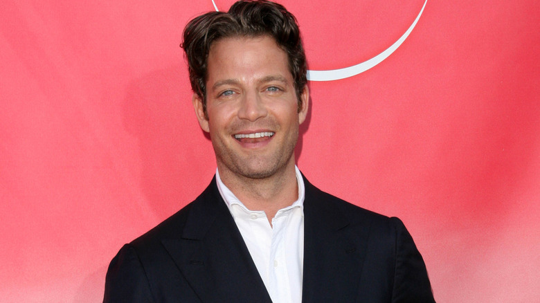 Nate Berkus mỉm cười trước ống kính trên nền đỏ