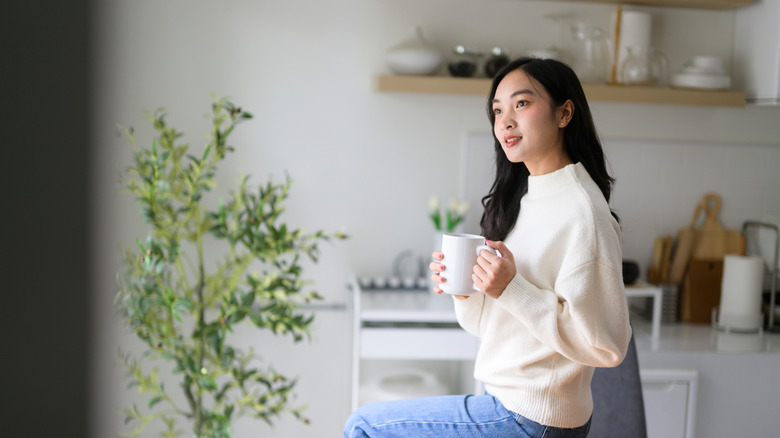 Một người phụ nữ mỉm cười và suy ngẫm trong bếp