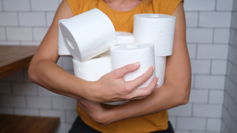 Một người cầm cuộn giấy vệ sinh trong phòng tắm