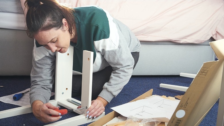 Người phụ nữ đang lắp ráp đồ nội thất IKEA trên sàn nhà