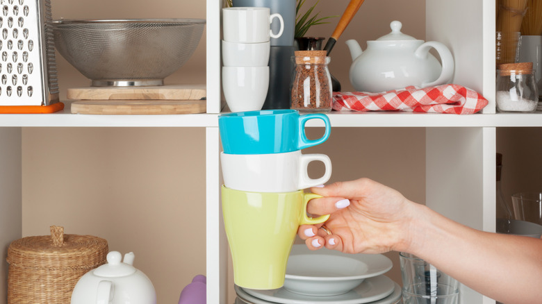 Một tay cầm những cốc cà phê xếp chồng lên nhau