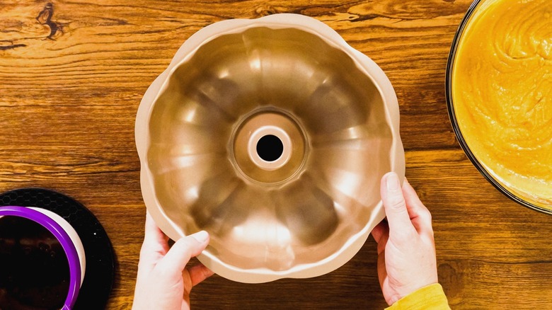 Người đặt chảo Bundt xuống mặt bàn gỗ