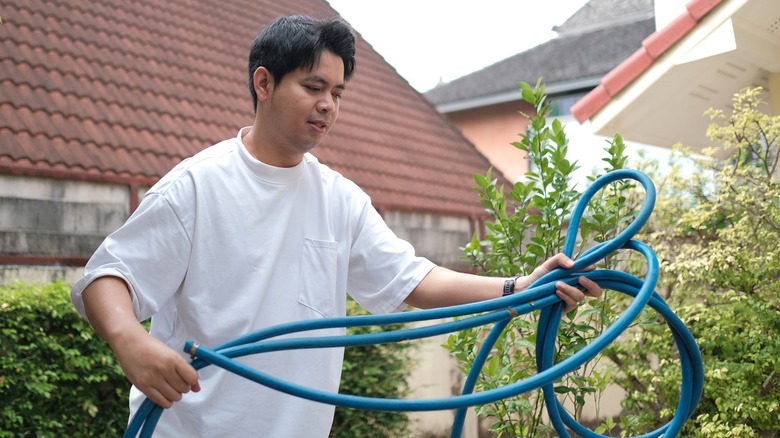 Người đàn ông đang cố gắng làm sạch cái vòi tưới vườn bị rối
