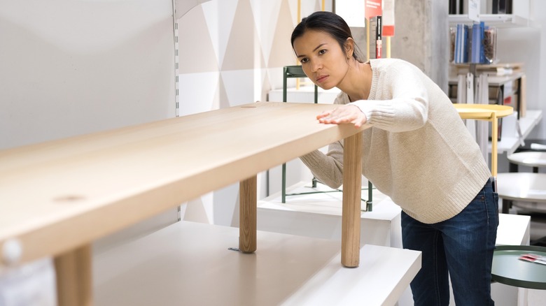 Người phụ nữ đang kiểm tra chiếc ghế gỗ trong phòng trưng bày IKEA