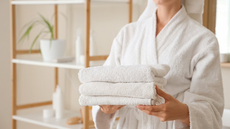 Người phụ nữ mặc áo choàng trắng cầm chồng khăn gấp