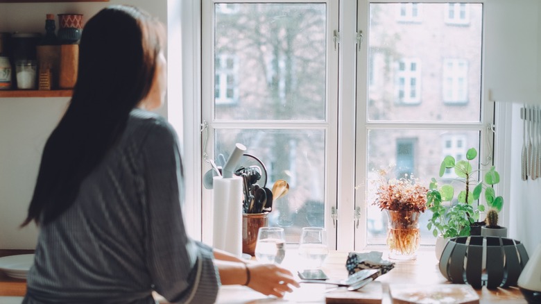 Người nhìn ra cửa sổ bếp vào một ngày tươi sáng