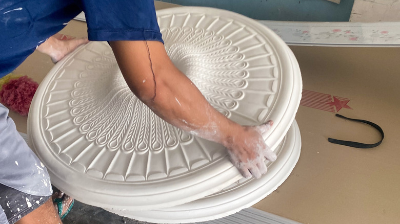 Một người đang nhặt huy chương trần nhà để lắp đặt