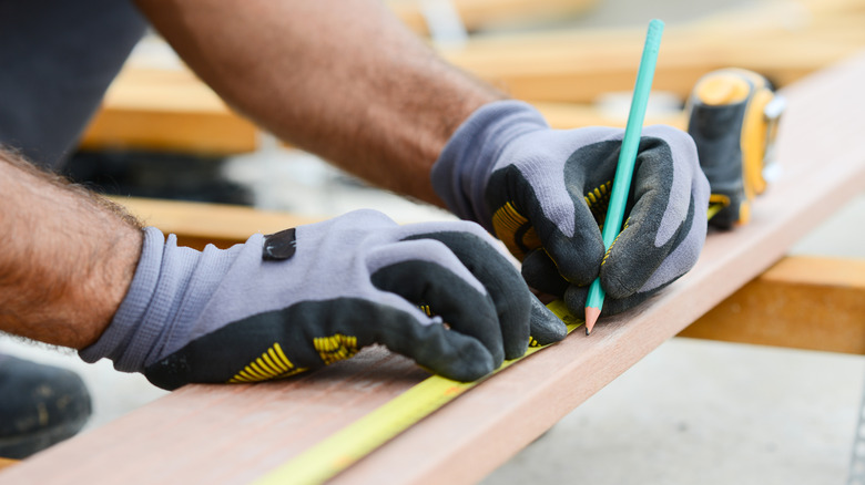 Người đo tấm gỗ phẳng trước khi cắt