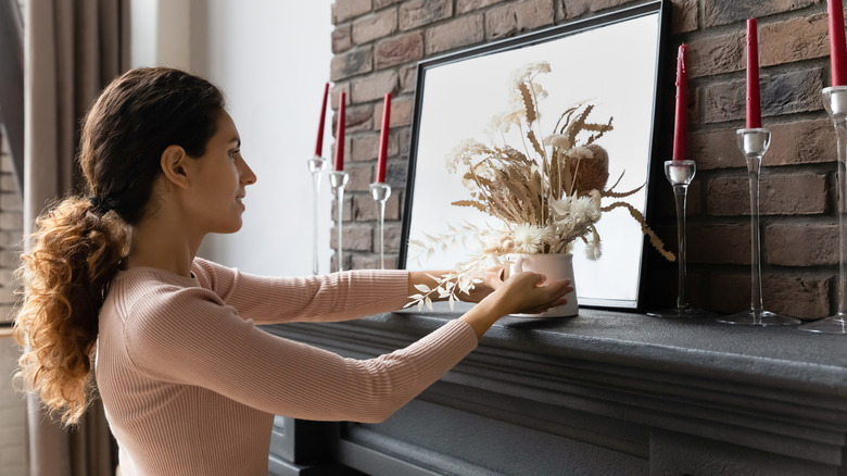 Người phụ nữ sắp xếp đồ trang trí trên lò sưởi